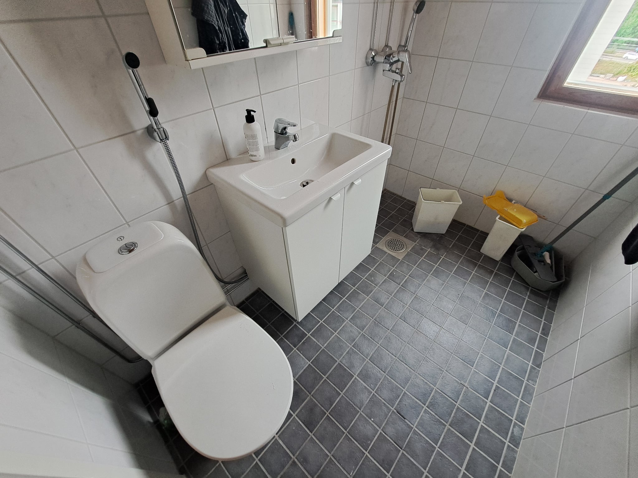 Kylpyhuoneen remontti, jossa on harmaa laattalattia ja valkoinen allaskaappi.