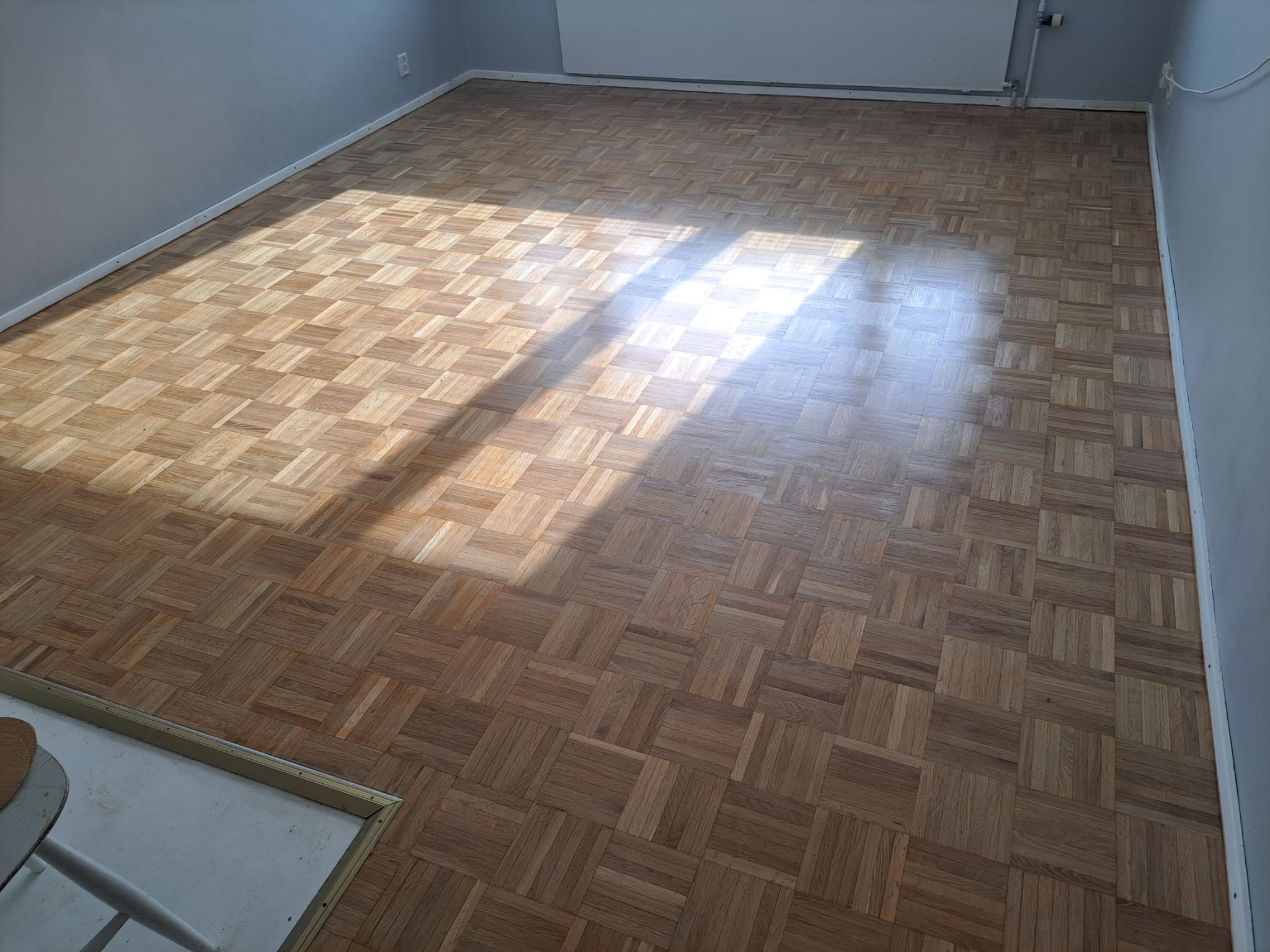 Parquet wood flooring installation in an empty room with a natural wood finish