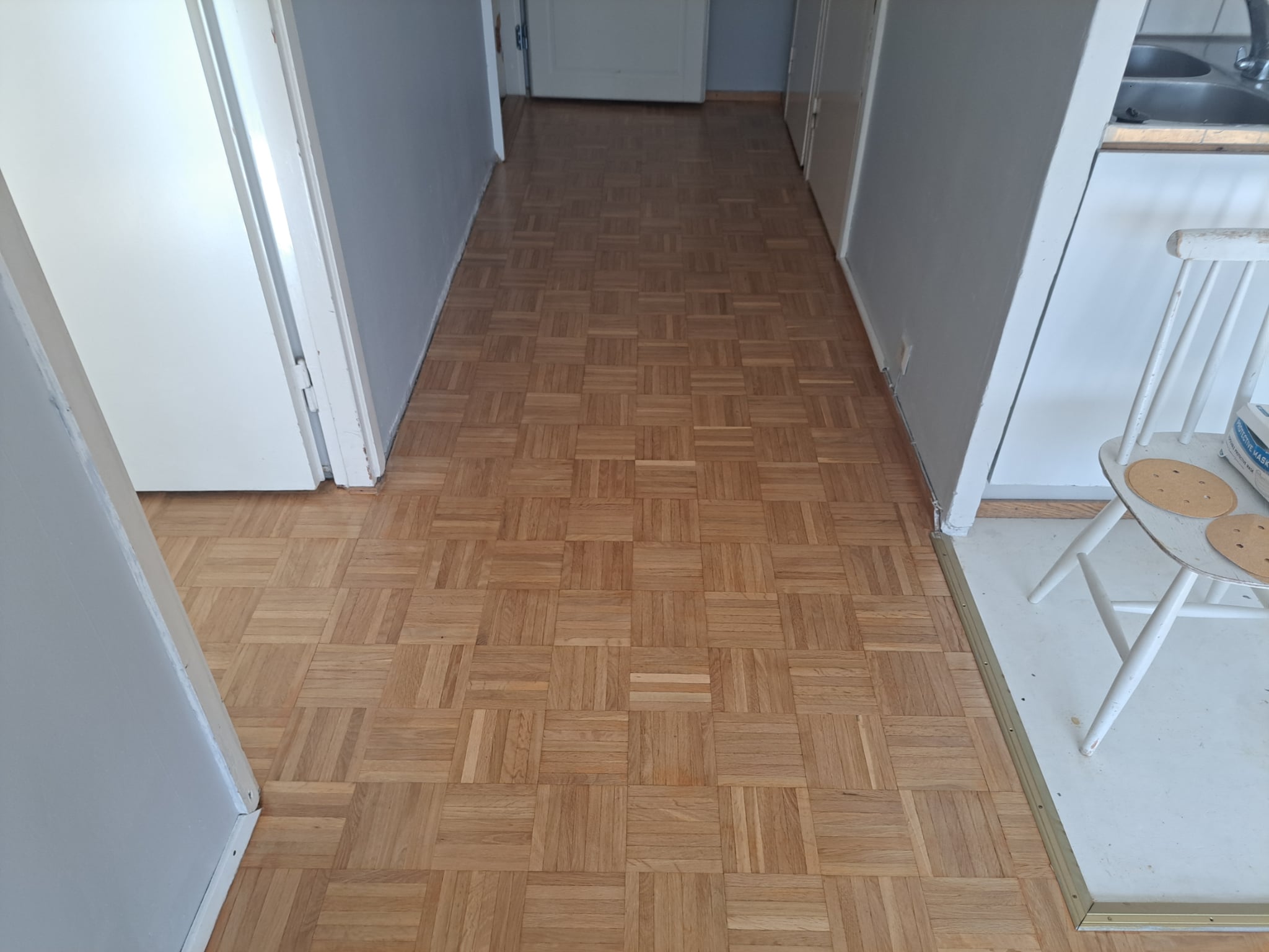 “Parquet wood flooring installation in a hallway with a natural oak finish