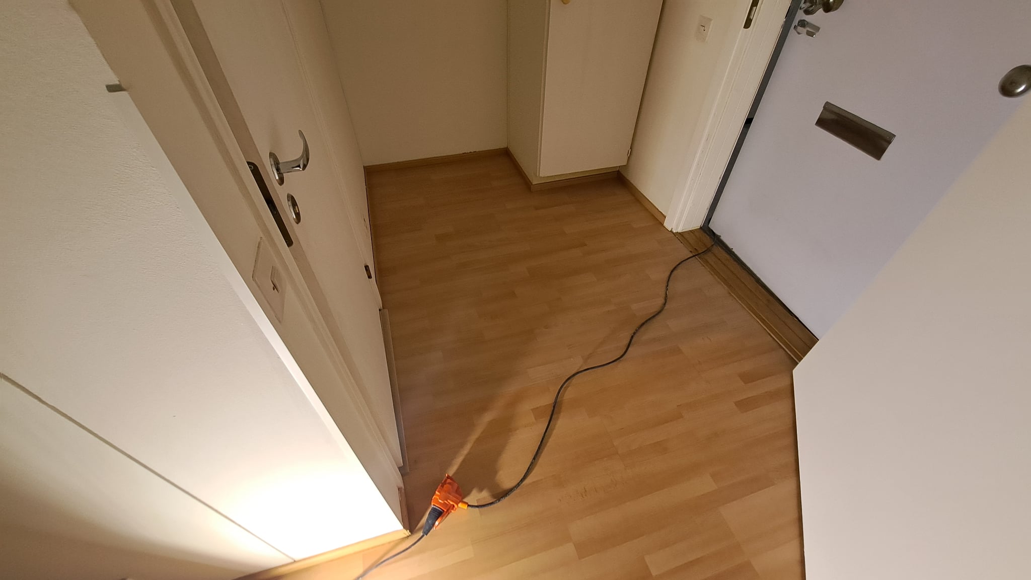 Valoisa huone, vaaleat seinät, puulattia ja suuret ikkunat.