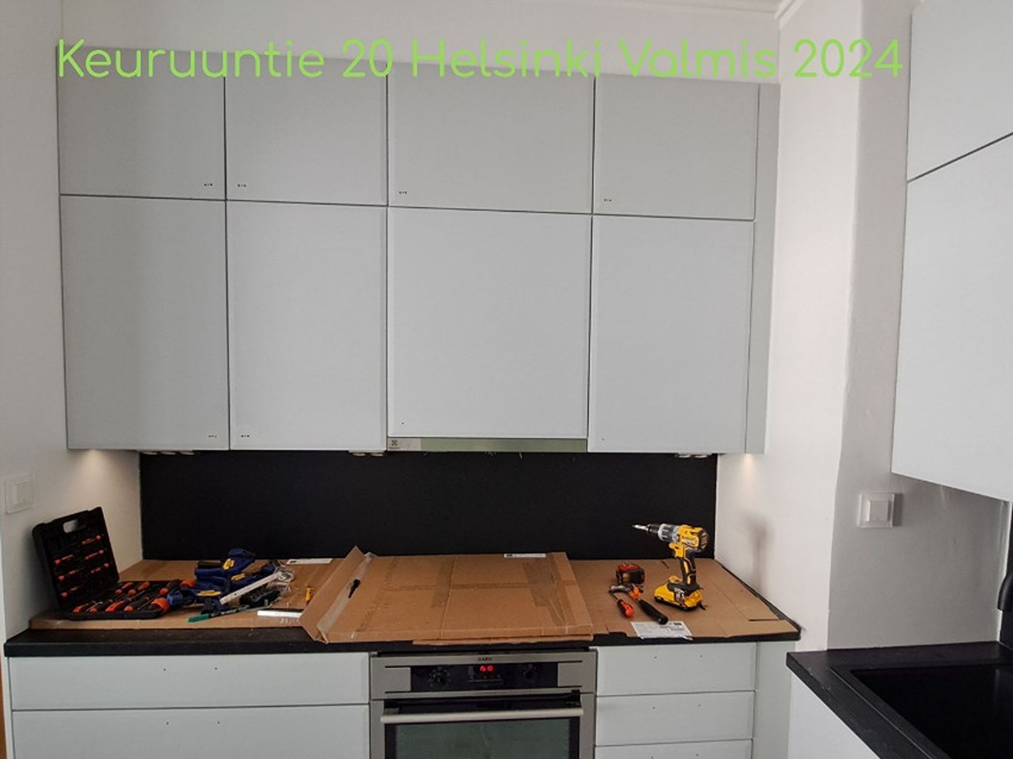 Valkoiset keittiökaapit, puinen työtaso, musta välitila ja kalusteisiin integroitu uuni keittiöremontin yhteydessä Helsingissä