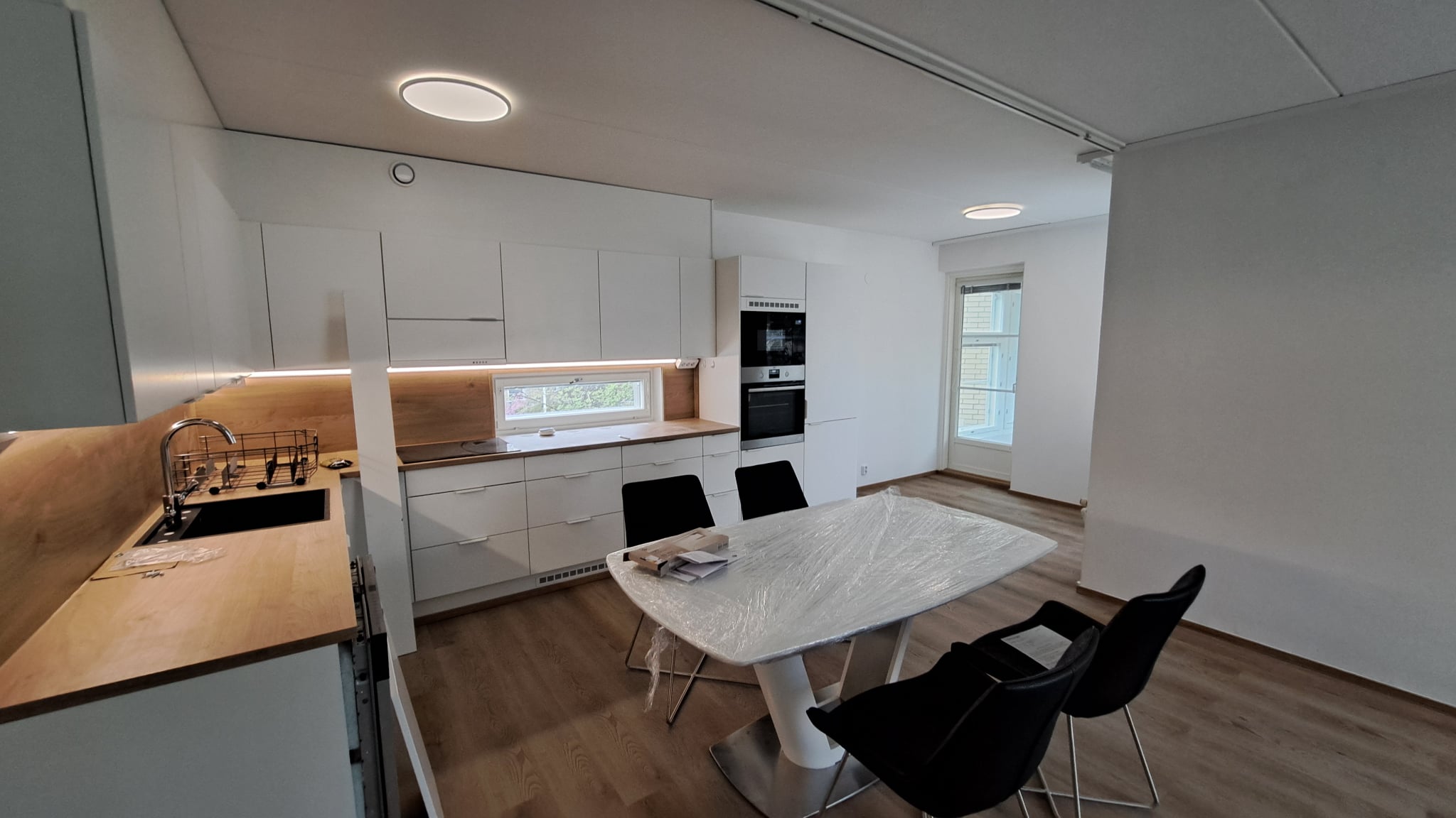 Helsinkiläisen keittiön remontti, jossa on vaaleat kaapistot, puiset työtasot ja moderni ruokailuryhmä.