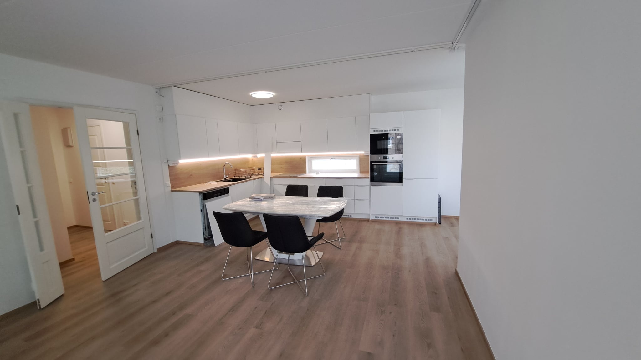 Uudistettu keittiö Helsingissä, jossa on vaaleat kaapistot, puinen työtaso ja moderni ruokailutila.