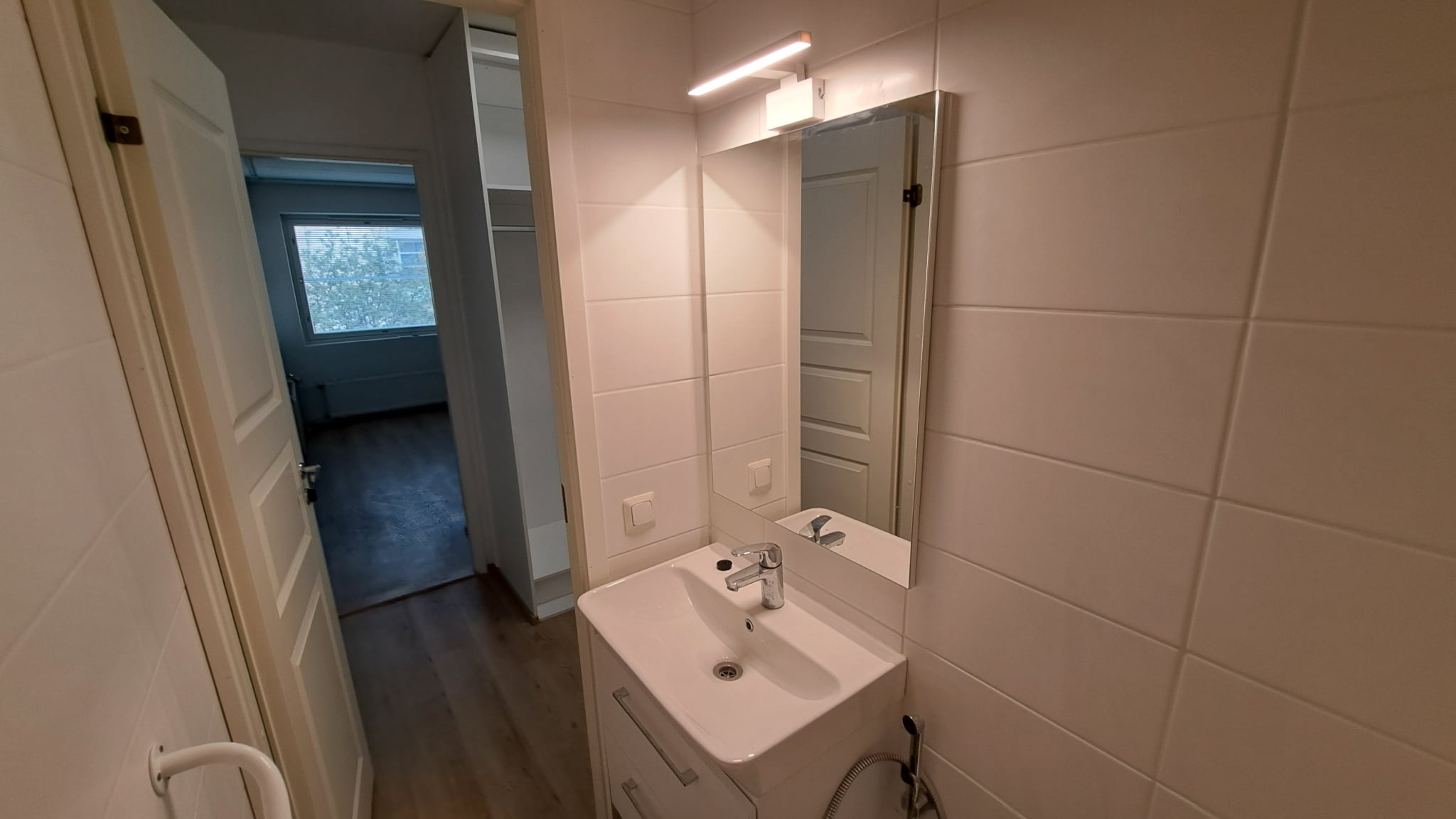 Kylpyhuoneremontti Helsingissä, jossa on moderni allaskaappi, peili ja vaaleat pintamateriaalit.