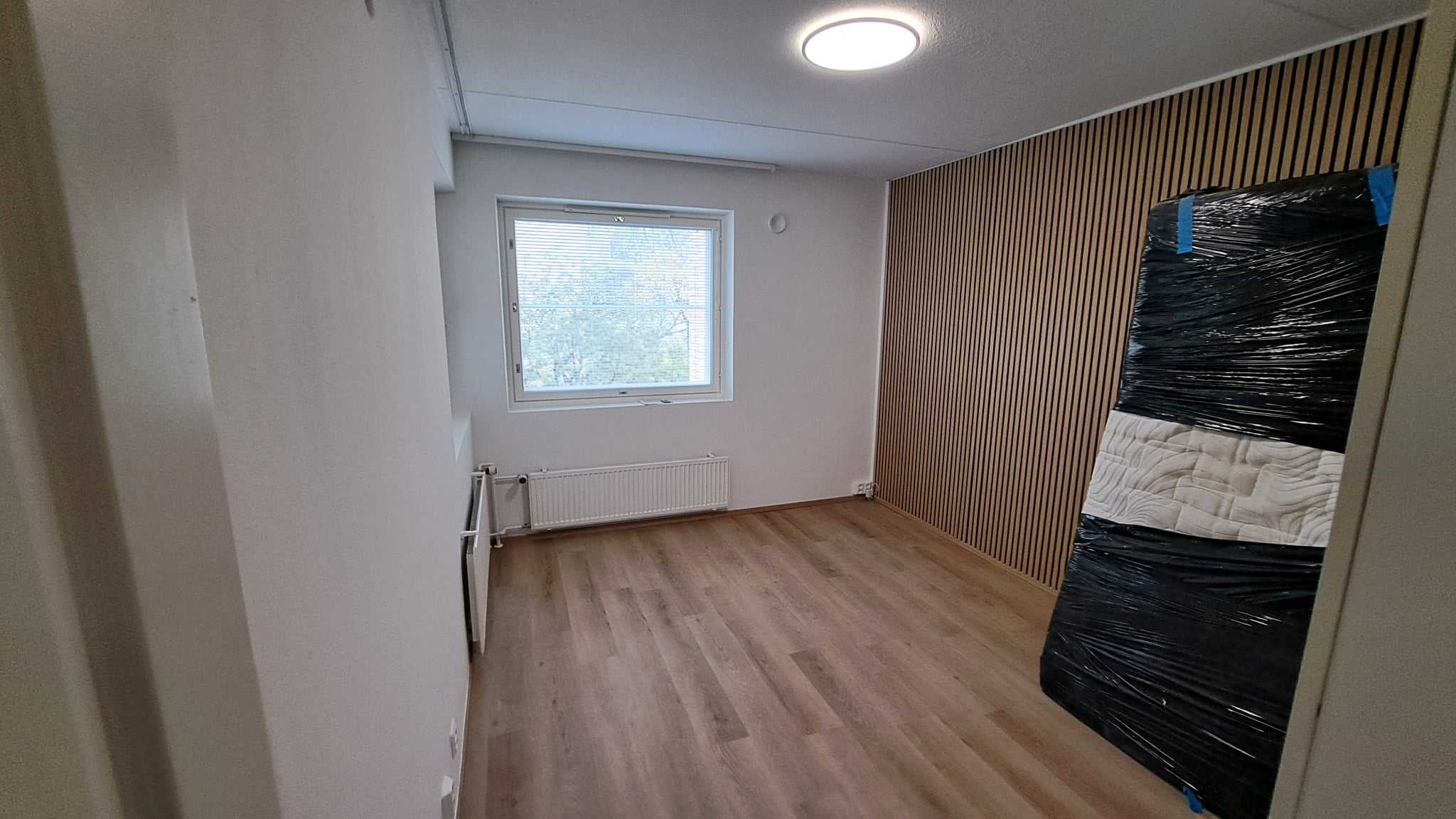 Remontoitu huone Helsingissä, jossa on vaaleat seinät, puunsävyinen lattia ja siistit sisäpinnat.