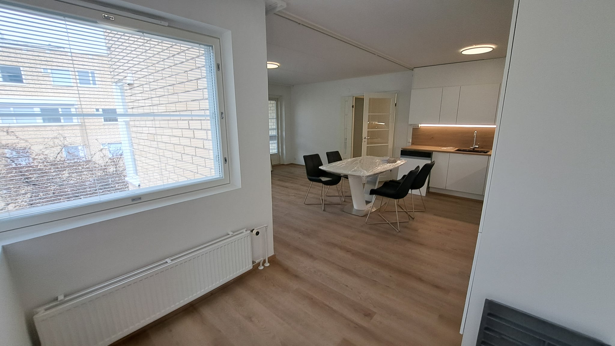 Kunnostettu huoneisto Helsingissä, jossa on suuret ikkunat, vaaleat seinät ja puunsävyinen lattia.
