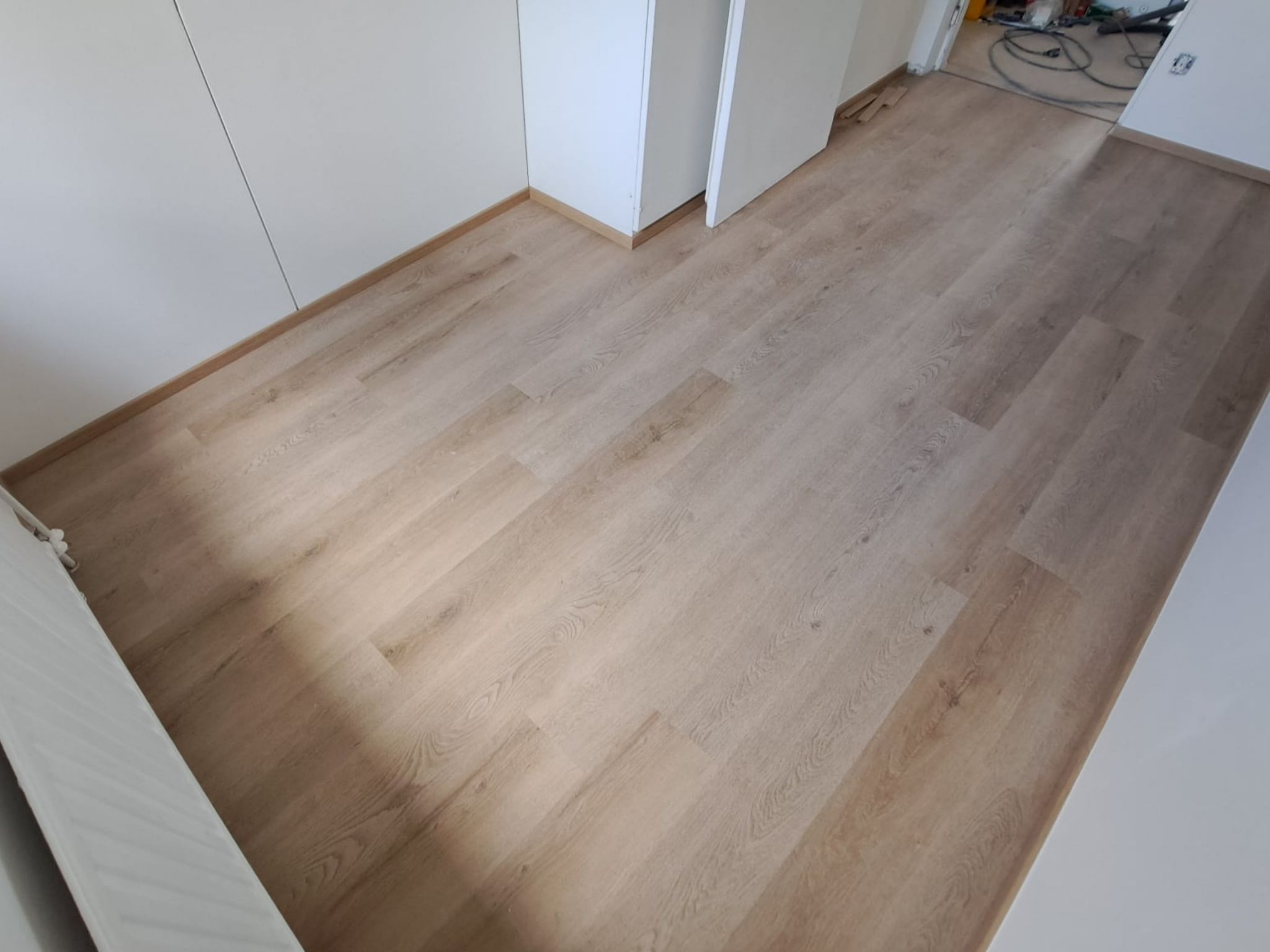 Lattiaremontin lopputulos Helsingissä, jossa vaalea puunsävyinen lattia yhdistyy valkoisiin seiniin.
