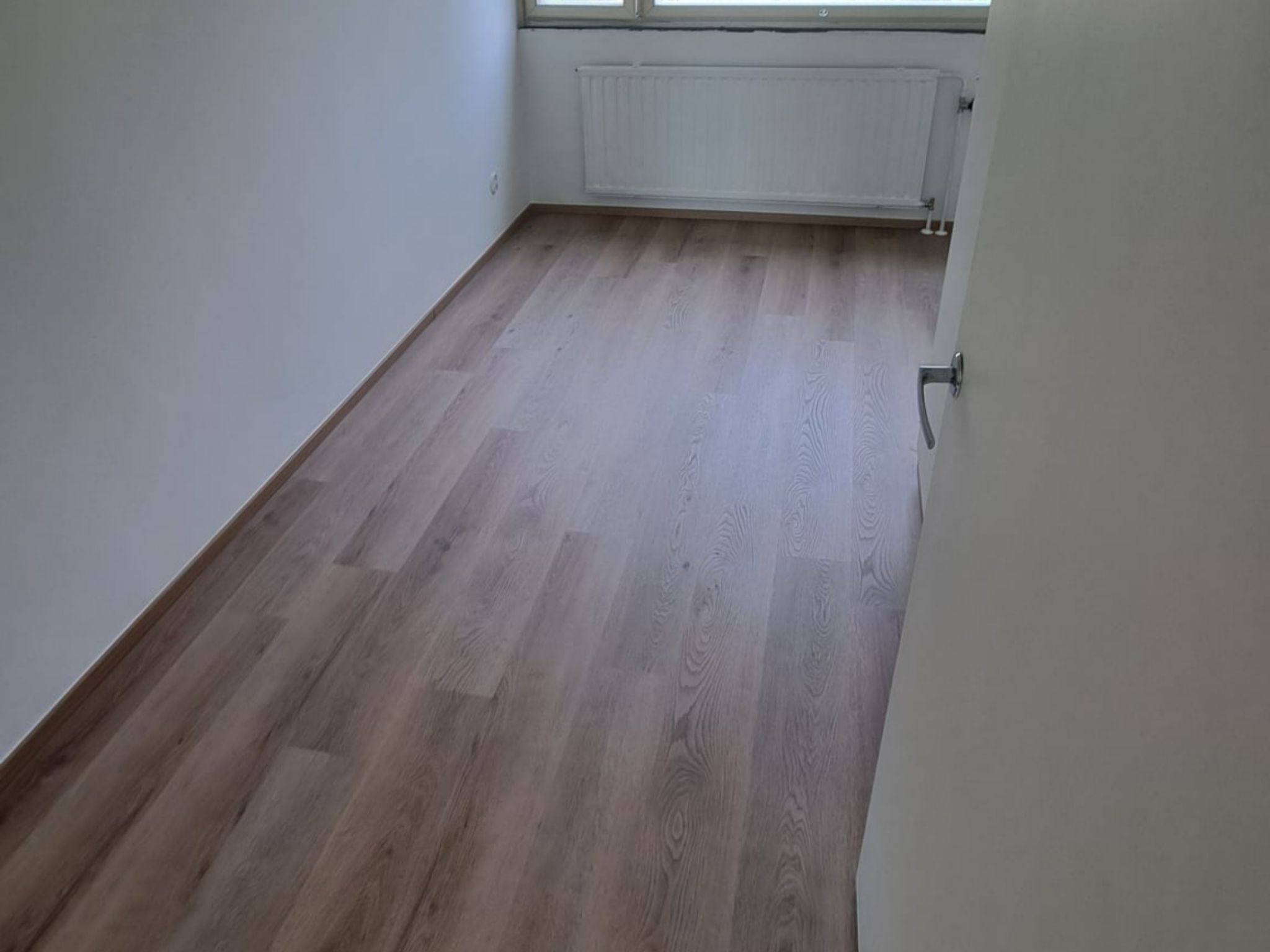 Remontoitu huoneisto Helsingissä, jossa on vaalea puulattia ja siistit seinäpinnat.