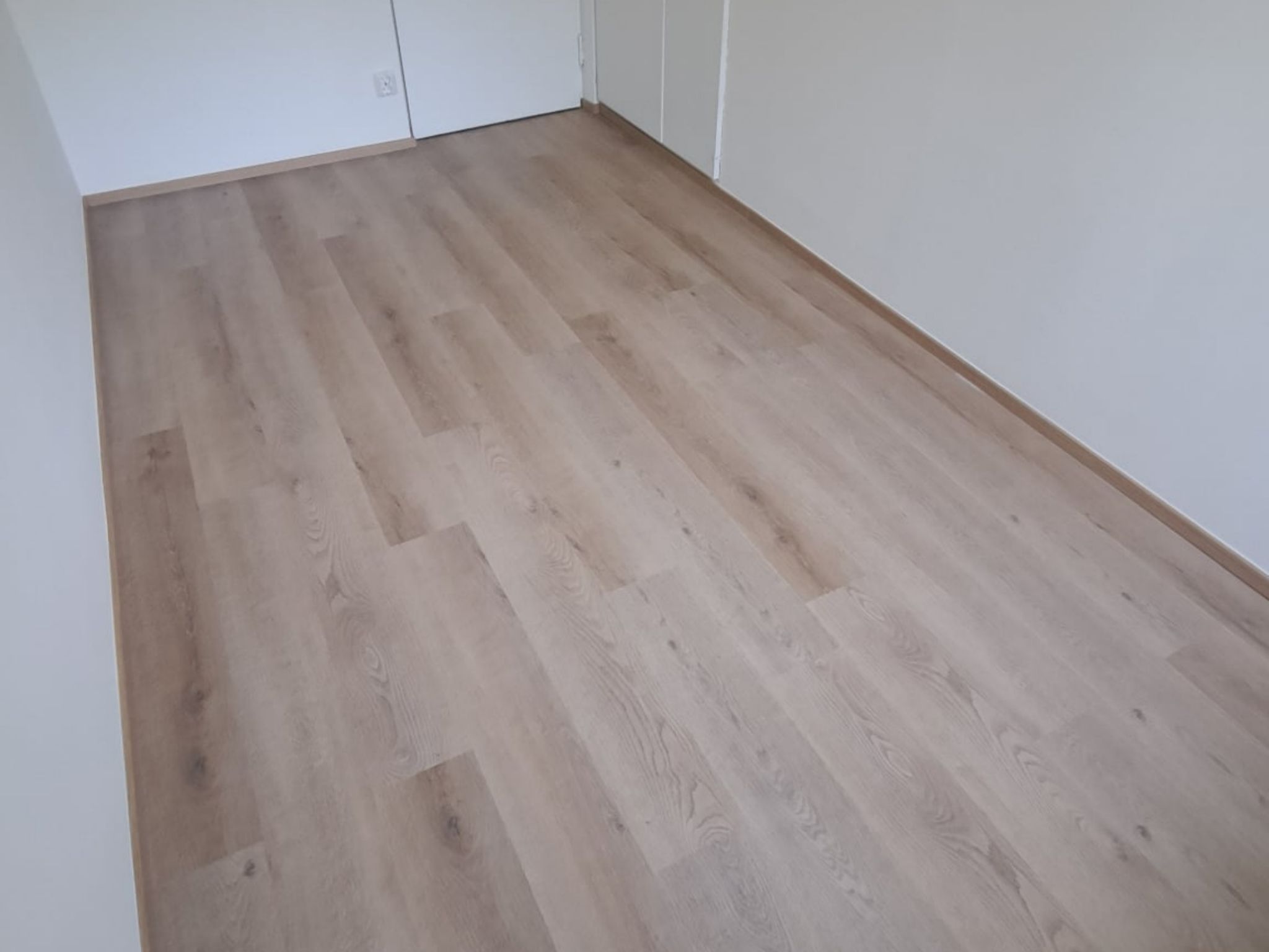Vaalea puulattia asennettuna remontoituun huoneeseen Helsingissä.