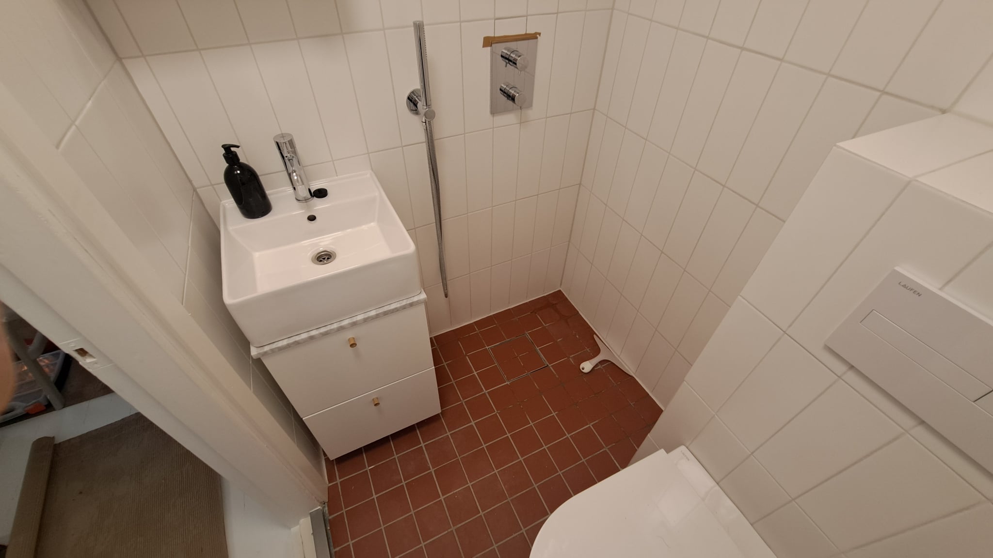 allaskaappi, pesuallas ja laatoitettu kylpyhuoneen lattia.